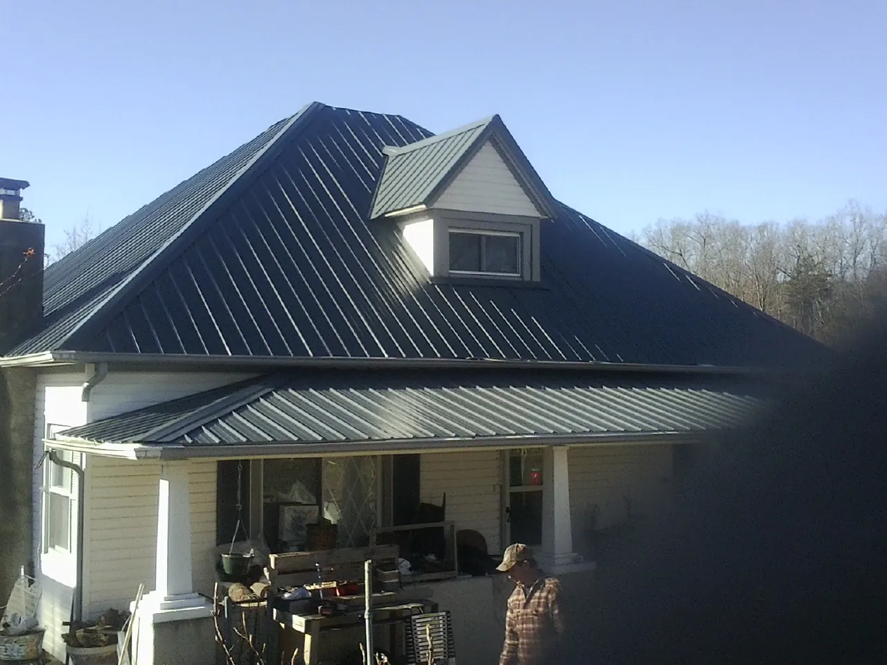 Dark blue standing seam metal roof with a dormer above a front porch in Elliott