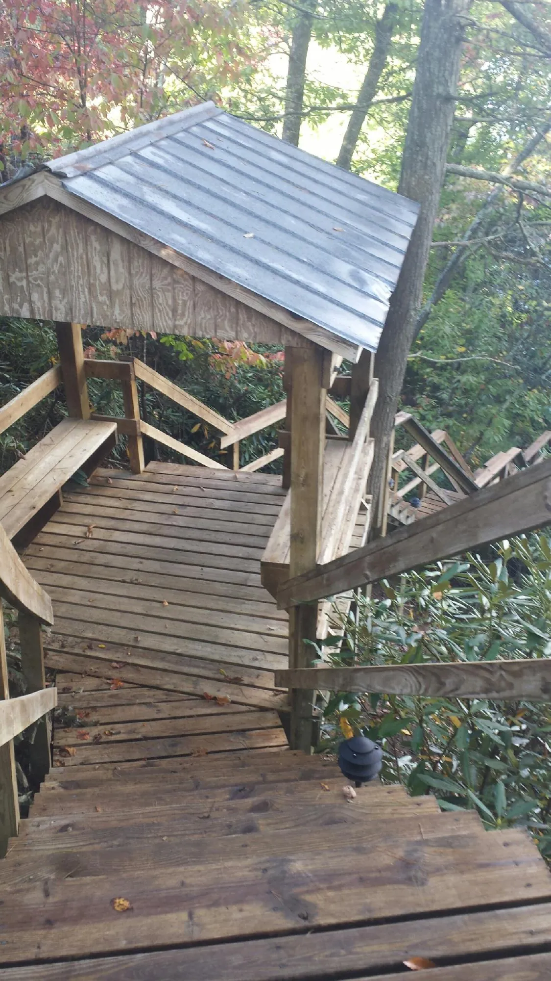 Metal roofed shelter over wooden steps on a wooded walkway — Skylight Repair & Installation work by our crew in Elliott