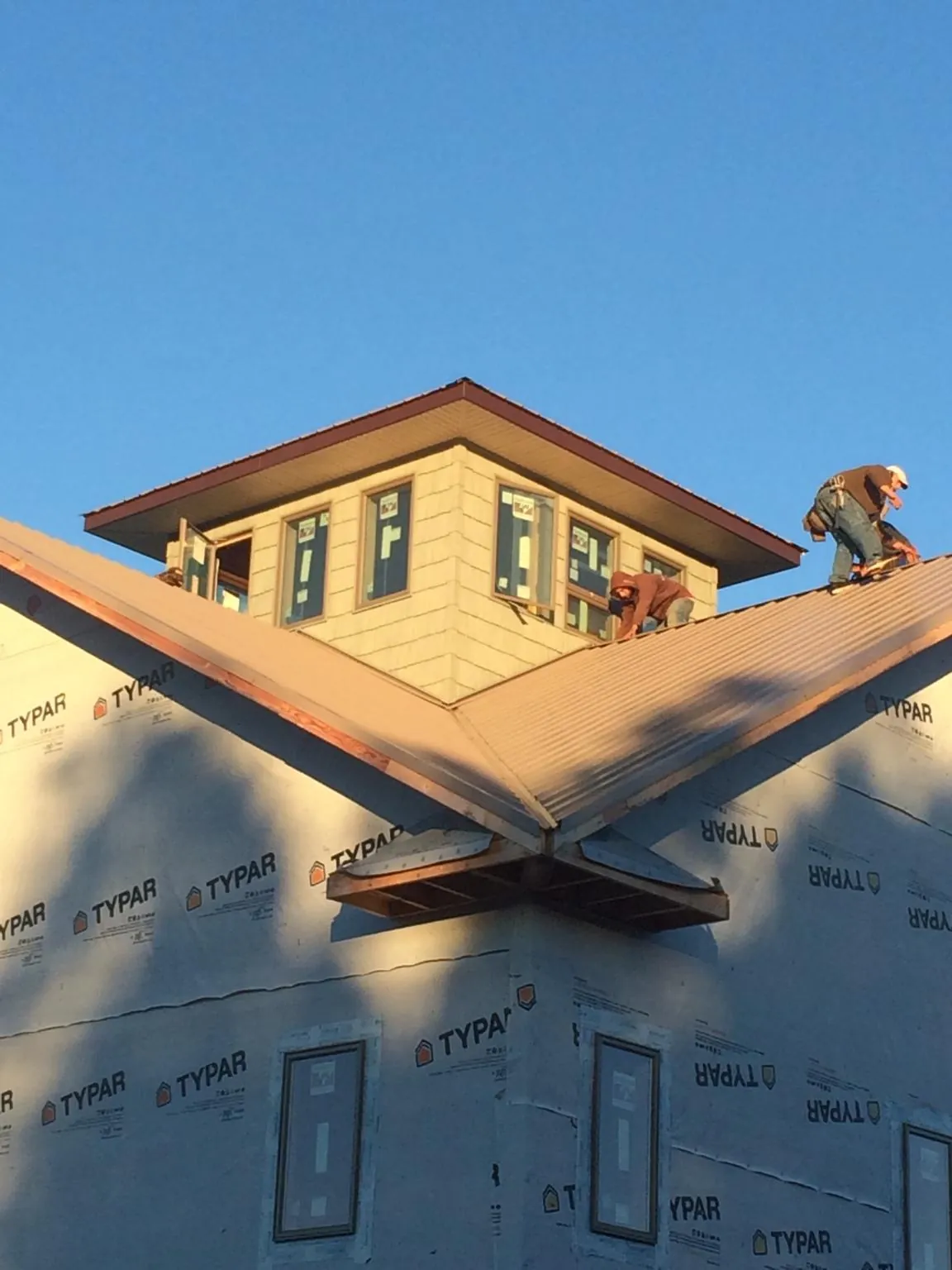Roofers working around a rooftop cupola on a new metal roof at sunset — Roof Waterproofing in Elliott by Roofing Brothers